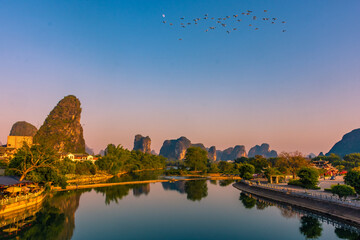 Flock of birds flying over the Li River in Yangshuo at sunset, China