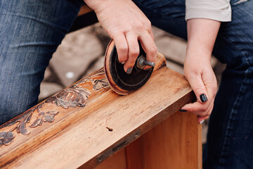macro women's hands sand an old wooden box with a floral pattern, removing the old polish and...