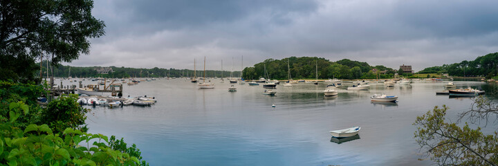 Fototapeta na wymiar Seascape panorama with moored boats in the bay. Dramatic cloudscape over the tranquil marina. Mooring yachts and boats.