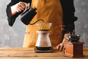 Barista making a drip coffee, pouring hot water from kettle over a ground coffee powder