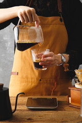Barista making a drip coffee, pouring finished hot coffee into a cup