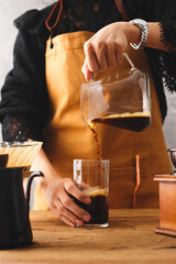 Barista making a drip coffee, pouring finished hot coffee into a glass