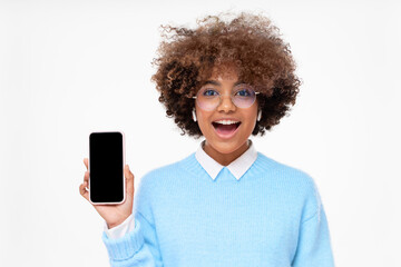 Surprised african girl excited by ads she is showing on blank phone screen with copy space,...