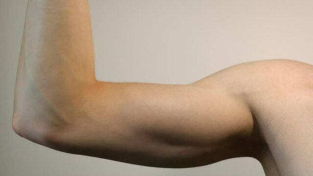 Young adult man flexing and extending biceps in closeup, isolated 4k human body part