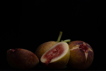 Photo of figs on a wooden board with a black background.
