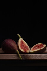 Photo of figs on a wooden board with a black background.