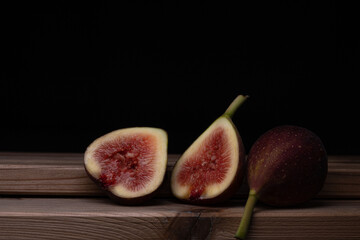 Photo of figs on a wooden board with a black background.
