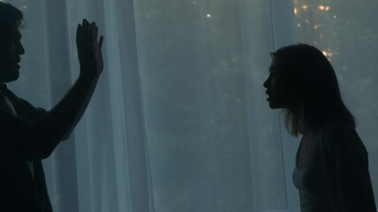 Aggressive wife screaming at husband, fighting, couple quarreling in the evening at home man and woman shouting at each other, gesturing. Scandal and crisis in family. Domestic violence, abuse.