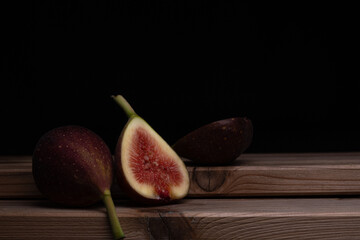 Photo of figs on a wooden board with a black background.