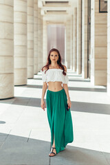 A full length red haired Caucasian girl strolls through a modern building