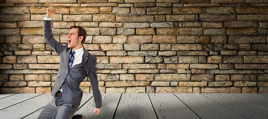 happy businessman on a wooden floor in front of a brick wall