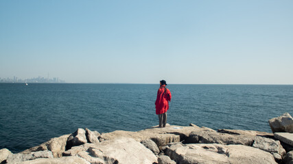 Fototapeta na wymiar Pirate in red dress looking at the city across the ocean