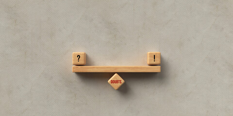 cubes forming a wooden scale balancing a question mark and an exclamation mark on a cube with the...