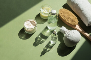 Body treatment and spa concept. Scrub, mask, cream and natural oil cosmetics on green background....