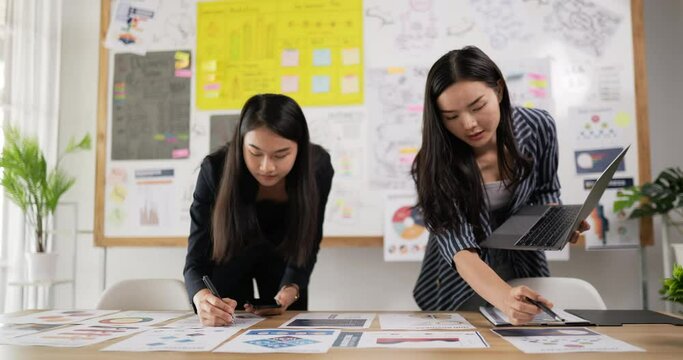 Two asian women checking to task