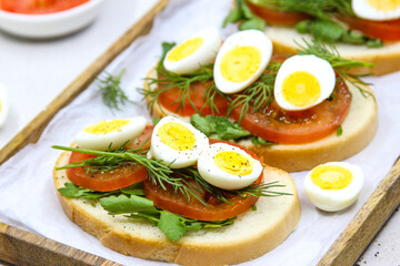 Fresh toast sandwiches with quail eggs, tomatoes and green herbs. Closeup. Top view. Copy space.