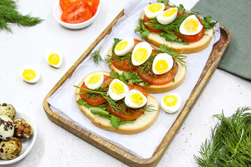 Fresh toast sandwiches with quail eggs, tomatoes and green herbs. Closeup. Top view. Copy space.