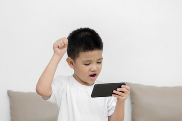 Happy little boy having fun playing game on mobile phone, Preschool kid sitting on sofa with smiling face watching cartoon on smartphone, Child using cell phone while relaxing at home