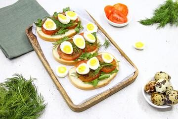 Fresh toast sandwiches with quail eggs, tomatoes and green herbs. Closeup. Top view. Copy space.