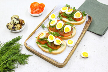 Fresh toast sandwiches with quail eggs, tomatoes and green herbs. Closeup. Top view. Copy space.
