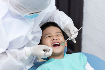 Fototapeta premium Dentist examining Asian little boy teeth in clinic.