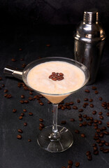 Irish cream cocktail and coffee in a glass with coffee beans on top on a black marble surface and coffee beans. black background with copy space for advertising. close up view