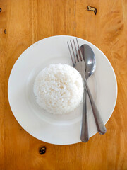 Rice on a plate with spoon and fork. On a wooden table. Photo about food.