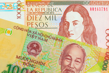 A macro image of a brown ten thousand bank note from Colombia paired up with a colorful, plastic ten thousand dong note from Vietnam.  Shot close up in macro.
