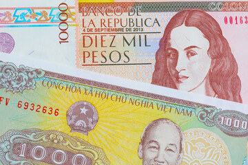 A macro image of a brown ten thousand bank note from Colombia paired up with a yellow one thousand dong bill from Vietnam.  Shot close up in macro.