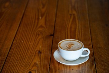 Cup cappuccino on textured wooden table with copy space.