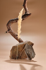 a scene for an advertising photo made of natural ingredients: sandstone stones, cossna twig and pampas grass on a beige background