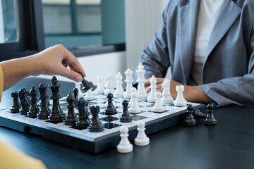 The hands of businesswomen two people moving chess in chess competitions demonstrate leadership, followers, and strategic plans, business success building processes, and teamwork