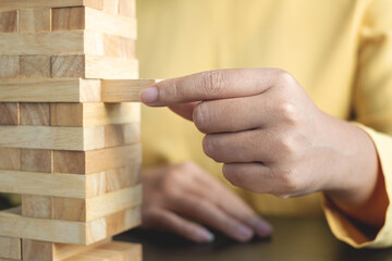 Hands of businesswomen playing wooden block game. Concept Risk of management and strategy plans for business growth and success