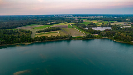 Obraz premium Aerial view of a beautiful and dramatic sunset over a forest lake reflected in the water, landscape drone shot. Blakheide, Beerse, Belgium. High quality photo