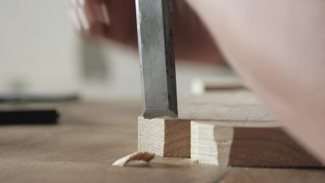 A wood carver cuts the edges of a wood board with a flat chisel. wood craftsman working with chisel. using hand carpentry tools