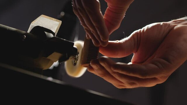 close-up. wood craftsman polishes a handmade wooden beard comb on a polishing machine. making a wooden beard comb. woodworking concept