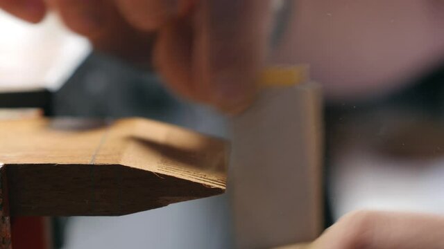 craftsman grinds teeth on a wooden comb with sanding paper. making a wooden beard comb. work with hand carpentry tools