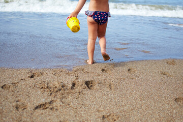 A little girl runs along the beach to the sea. Footprints of children's feet in the sand.