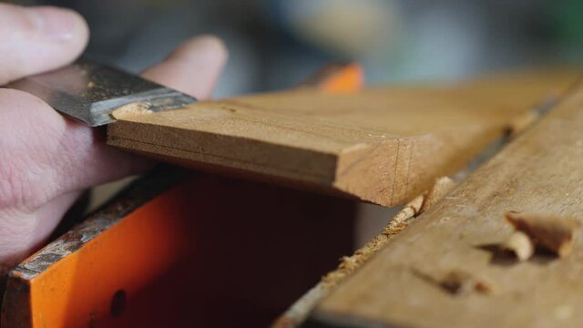 woodworker removes excess thickness from a wooden board with a flat chisel. making wooden beard combs. chisel work