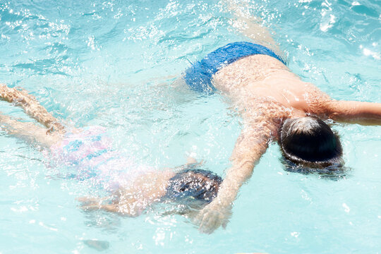 Drowning kid into swimming pool water, close-up