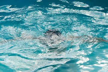 Drowning kid into swimming pool water, close-up
