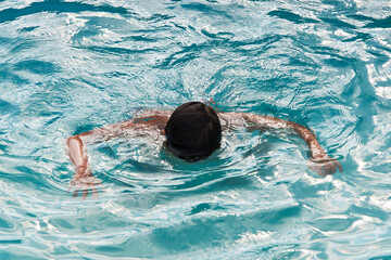 Drowning kid into swimming pool water, close-up