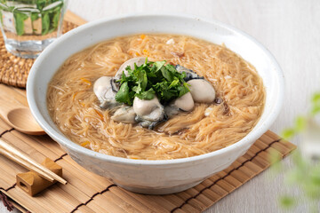 Delicious oyster vermicelli in a bowl on wooden table background.
