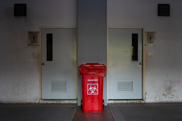 Infected trash in front of the bathroom,One red infectious waste bin at a public toilet.