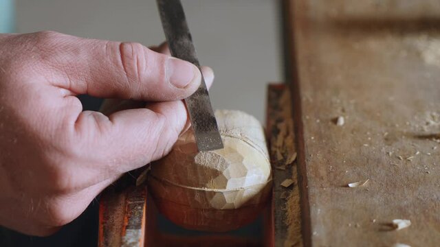 a woodcarver carves a robot or knight helmet with a chisel. wood carving in a carpentry workshop. the art of woodcarving and woodworking. the sound of hand carpentry tools