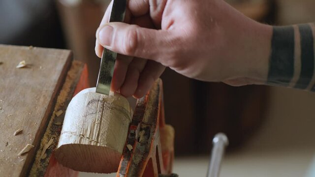 a woodcarver carves a robot or knight helmet with a chisel. wood carving in a carpentry workshop. the art of woodcarving and woodworking. the sound of hand carpentry tools