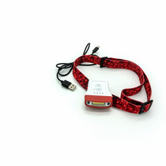 Flashlight for a cyclist. Wi-Fi connection and light control buttons on the case. Red elastic headband. Wire with usb connector for charging. Isolated on a white background.