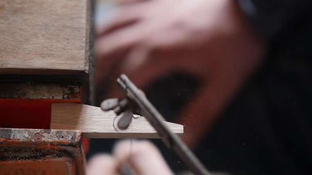 a carpenter cuts a piece of wood with a hand jigsaw. wood carving in a carpentry workshop. the art of woodworking. the sound of hand carpentry tools