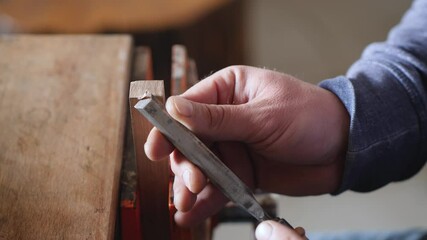 A carpenter removes chamfer from a piece of wood with a chisel. woodworker working with a chisel. hand carpentry tools