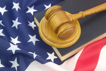 Wooden judge gavel with legal book on USA flag. US court concept.	